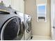 Bright laundry room with modern gray washer and dryer appliances next to a window and white storage cabinets at 6111 Horse Mill Pl, Palmetto, FL 34221