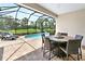 Outdoor dining and lounge area with a screened-in pool and tropical landscaping at 6317 Rivo Lakes Blvd, Sarasota, FL 34241
