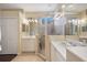 Bright bathroom showcasing dual sinks, walk-in shower, neutral tile, and a linen closet at 7439 Sea Island Ln, University Park, FL 34201