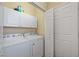 Practical laundry room with washer, dryer, white storage cabinets and an open closet at 7439 Sea Island Ln, University Park, FL 34201