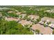 Aerial view of homes with terra cotta tile roofs nestled among lush landscaping and mature trees at 7470 Botanica Pkwy # 201B22, Sarasota, FL 34238