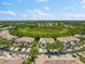 An aerial view of a neighborhood featuring terra cotta tile roofs, lush landscaping, and ponds at 7470 Botanica Pkwy # 201B22, Sarasota, FL 34238