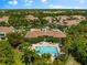 An aerial view showcasing a community pool surrounded by lush greenery, palm trees, and well-maintained homes at 7470 Botanica Pkwy # 201B22, Sarasota, FL 34238