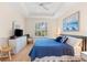 Serene bedroom featuring a tray ceiling, shuttered windows, TV, and comfortable seating at 7470 Botanica Pkwy # 201B22, Sarasota, FL 34238