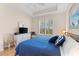 Bright bedroom with a tray ceiling, shuttered windows, TV, and a cozy armchair for relaxing at 7470 Botanica Pkwy # 201B22, Sarasota, FL 34238