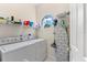 Bright laundry room featuring front-load washer, dryer, storage shelves, and a circular window for ample natural light at 7470 Botanica Pkwy # 201B22, Sarasota, FL 34238