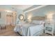 Bright bedroom with wood floors, round mirror, white furniture, and updated bathroom access at 750 N Tamiami Trl # 304, Sarasota, FL 34236