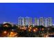 Nighttime exterior view of two high-rise condo buildings from ground level surrounded by lush tropical landscaping at 750 N Tamiami Trl # 304, Sarasota, FL 34236