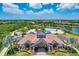 Community clubhouse with tile roof, manicured landscaping, and a view of the pool, lake, and golf course at 7643 Haddington Cv, Bradenton, FL 34202
