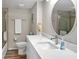 Modern bathroom features white cabinets, a round mirror, and tile flooring in neutral tones at 8710 Midnight Pass Rd # 202, Sarasota, FL 34242