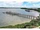Aerial view of a wooden dock extending into a calm body of water with lush green surroundings at 8710 Midnight Pass Rd # 202, Sarasota, FL 34242