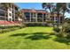Expansive grassy lawn framed by mature trees and vibrant tropical foliage near a condominium building at 8710 Midnight Pass Rd # 202, Sarasota, FL 34242