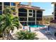 Inviting pool area surrounded by lounge chairs, tables, and lush tropical landscaping at 8710 Midnight Pass Rd # 202, Sarasota, FL 34242