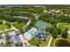 Scenic aerial view featuring tennis courts, a pool, community building, and a parking lot at 6314 Bay Cedar Ln # 201, Bradenton, FL 34203