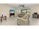 Open-concept living room featuring neutral tones, tile floors, a ceiling fan, and sliding glass doors at 10111 Malachite Dr, Bradenton, FL 34211