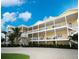 Multi-story yellow building with white railings, staircases, and mature palm trees at 1020 Sun N Sea Dr # 104B, Sarasota, FL 34242