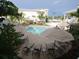 Community pool area featuring chaise lounge chairs and tables with umbrellas, set among lush tropical plants at 1020 Sun N Sea Dr # 104B, Sarasota, FL 34242