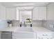Bright kitchen features stainless appliances, light colored backsplash, white cabinets and farmhouse sink at 1046 Greystone Ln, Sarasota, FL 34232