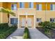 Exterior of yellow condos with white door frames, two doors, and landscaping at 12971 Tigers Eye Dr, Venice, FL 34292