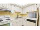 A kitchen featuring white cabinets, appliances, and a breakfast bar window at 1330 Glen Oaks E Dr # 374D, Sarasota, FL 34232