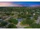 Sunset aerial view of a house surrounded by lush green trees, featuring a pool and a lovely neighborhood at 13615 4Th Ne Ave, Bradenton, FL 34212