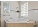 Bathroom featuring a large soaking tub with tiled surround and tiled walls with decorative border at 1828 Mova St, Sarasota, FL 34231