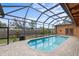Screened-in pool area with brick pavers, lush landscaping, and a clear blue pool at 1828 Mova St, Sarasota, FL 34231