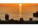 Spectacular beach sunset view with calm waters, beach chairs, and silhouettes of people enjoying the scenery at 2301 Gulf Of Mexico Dr # 26N, Longboat Key, FL 34228