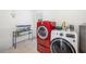 Bright laundry room featuring a red washer, a white dryer, and ample storage space at 2311 Sunnyside Pl, Sarasota, FL 34239