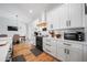 Bright kitchen featuring white cabinets, stainless appliances, tile backsplash, and hardwood floors at 2366 Ann Arbor Rd, North Port, FL 34286