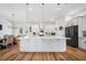 Bright kitchen features a large island with pendant lights, white cabinets, and a dining area at 2366 Ann Arbor Rd, North Port, FL 34286