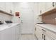 Functional laundry room with modern washer and dryer, counter space, utility sink, and ample cabinet storage at 2705 Taheebo Way, North Port, FL 34289