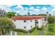 Low angle of a two-story condo complex with a red roof and lush, green landscaping on a bright, sunny day at 3500 Beneva Rd # 306, Sarasota, FL 34232