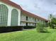 Exterior view of a two-story condo complex with green railings and a red roof on a bright, sunny day at 3500 Beneva Rd # 306, Sarasota, FL 34232