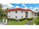 Low angle of a two-story condo complex with a red roof and lush, green landscaping on a bright, sunny day at 3500 Beneva Rd # 306, Sarasota, FL 34232