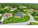 Aerial view of a charming yellow home with a green roof, surrounded by lush greenery and mature trees at 3530 Adelaide Ave, North Port, FL 34288