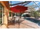 Outdoor dining area with an umbrella beside a screened-in pool and golf course, designed for a relaxing setting at 3941 Spyglass Hill Rd, Sarasota, FL 34238