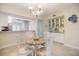 Dining room with chandelier, glass table, and view into the kitchen area at 400 Laurel Lake Dr # 104, Venice, FL 34292