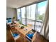 Staged dining area with wood table, blue-cushioned chairs, white sofas, and large sliding glass doors at 435 S Gulfstream Ave # 605, Sarasota, FL 34236