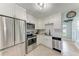 A bright kitchen features stainless steel appliances, white cabinets, and tiled floors with a large clock on the wall at 5732 Beneva Rd, Sarasota, FL 34233