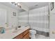 Clean bathroom featuring a wooden vanity, a full mirror, a shower with a striped curtain and white tile flooring at 5915 43Rd E Ct, Bradenton, FL 34203