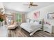 Bright bedroom featuring wood floors, neutral tones, a ceiling fan, and a chaise lounge near a window at 5915 43Rd E Ct, Bradenton, FL 34203
