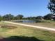 Scenic view of community lake with a walking path and lush landscaping at 6442 Tailfeather Way, Bradenton, FL 34203