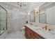 Elegant bathroom featuring double sink vanity, marble tile, and stylish gold fixtures, creating a luxurious and bright space at 6600 Horned Owl Pl, Sarasota, FL 34241