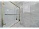 Shower with glass doors, gold trim and tiled walls, offering a modern and luxurious bathing experience in a sunlit space at 6600 Horned Owl Pl, Sarasota, FL 34241