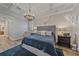 Bright bedroom with a tray ceiling, modern chandelier, and unique animal skull décor above the bed at 6600 Horned Owl Pl, Sarasota, FL 34241