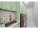 Well-equipped laundry room with green cabinets, modern washer and dryer, and white tile flooring at 6600 Horned Owl Pl, Sarasota, FL 34241