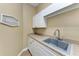 Laundry room with a sink, white cabinets and tile flooring at 7913 Osprey Hammock Ct, Sarasota, FL 34240