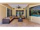 Outdoor patio featuring comfortable seating, ceiling fan, and sliding glass doors to screened pool area at 7913 Osprey Hammock Ct, Sarasota, FL 34240