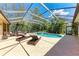 Screened-in pool area with lounge chairs, lush landscaping, and hot tub at 7913 Osprey Hammock Ct, Sarasota, FL 34240